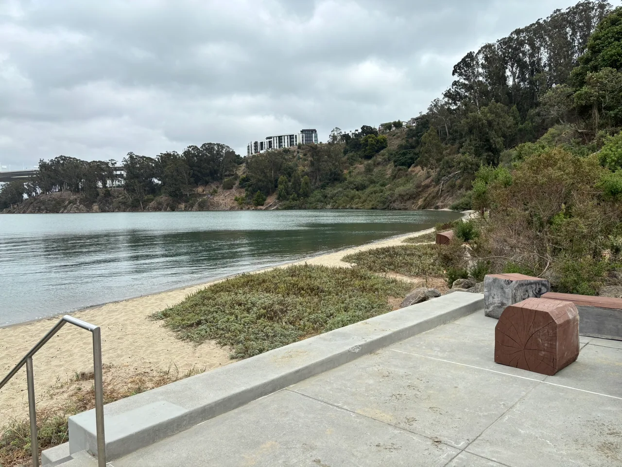 Concrete seating, planted slopes, and a paved path overlook Clipper Cove.