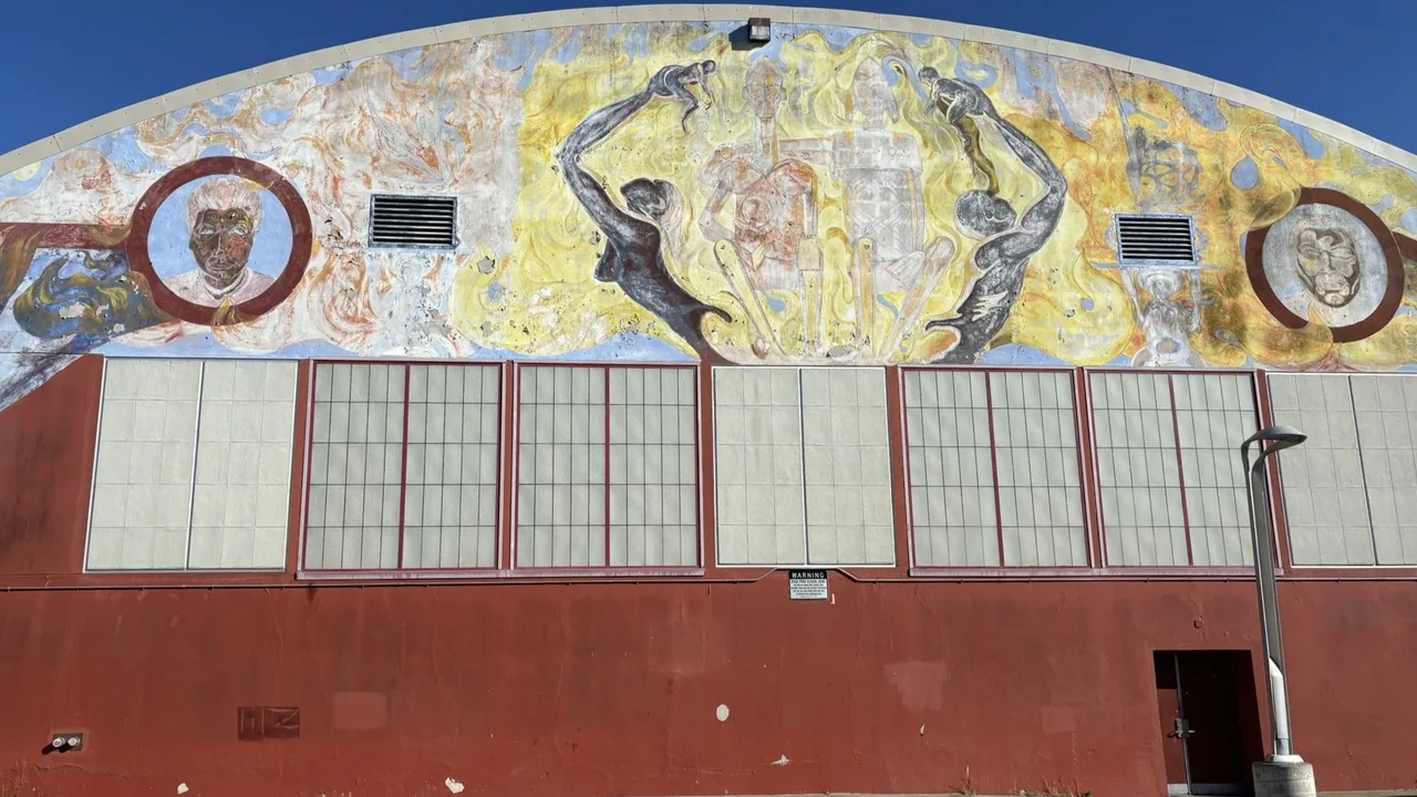 Weathered mural of figures and outstretched hands above the recreation center windows