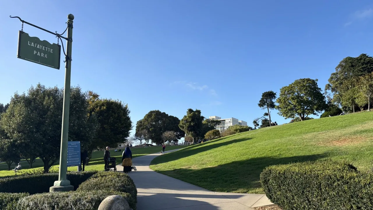 Lafayette Park sign beside a paved path climbing between green lawns