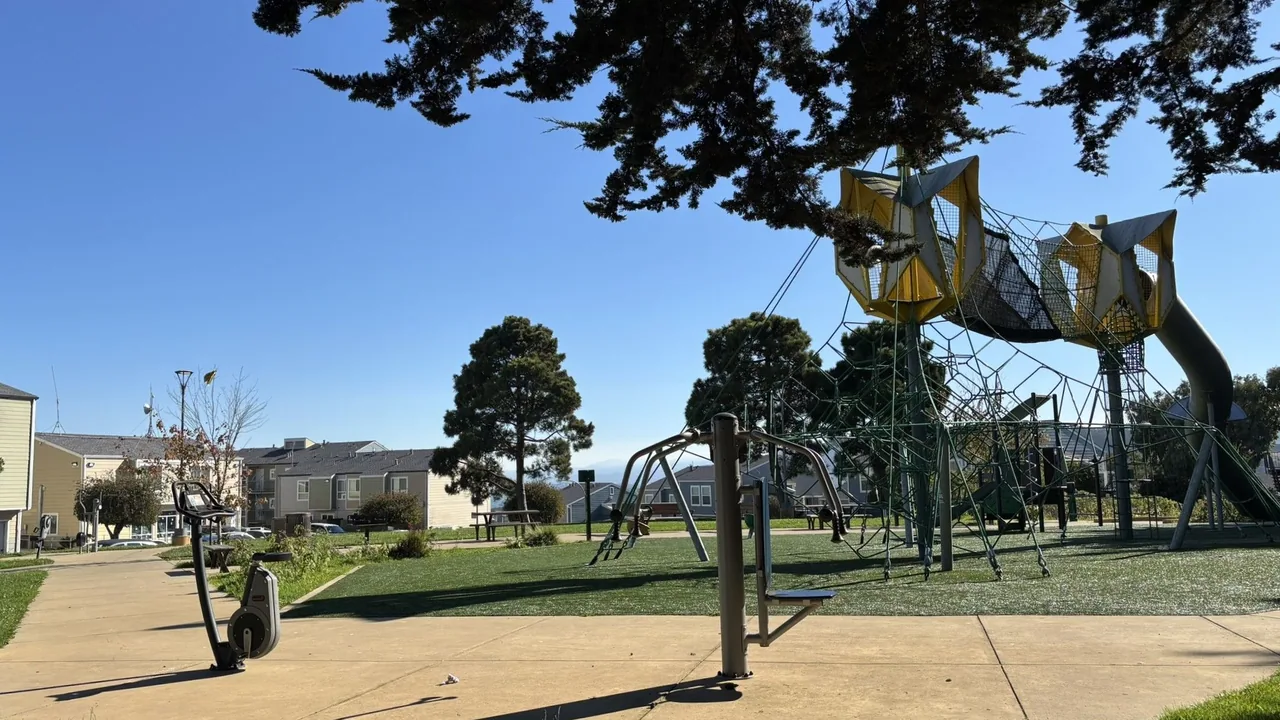 Rope climbing tower, swings, and outdoor exercise equipment on a sunny playground