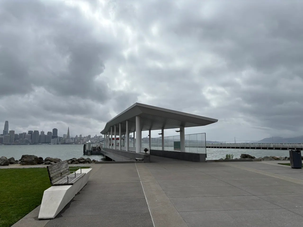 A waterfront pavilion on Treasure Island frames a view toward the San Francisco skyline.