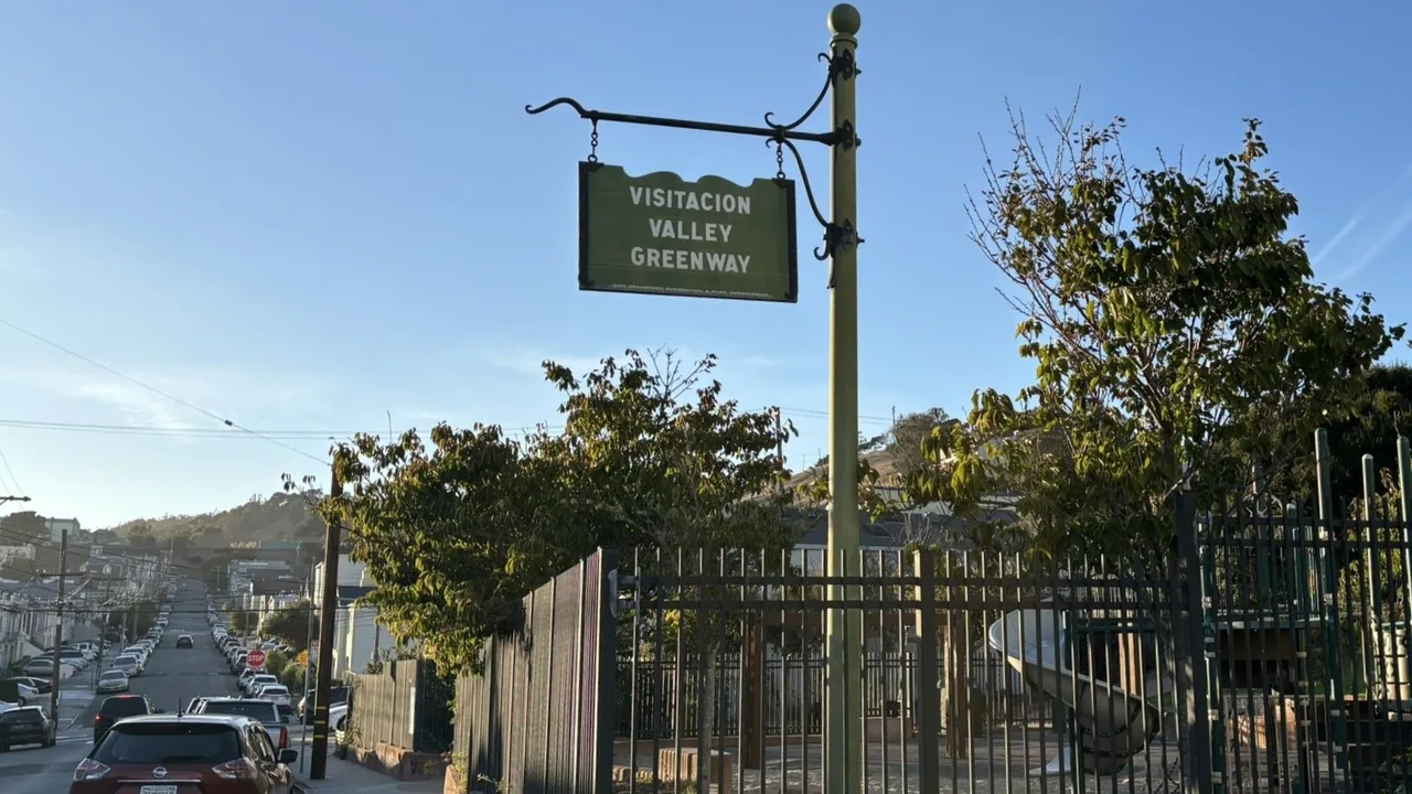 Visitacion Valley Greenway sign above a gated entrance on a sloping neighborhood street